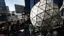 Awak media melihat pekerja menyelesaikan pemasangan bola kristal di atas sebuah gedung di Times Square, New York, Kamis (27/12). Menyaksikan bola kristal raksasa adalah tradisi yang tidak terlewatkan setiap perayaan tahun baru sejak 1907. (AP/Seth Wenig)