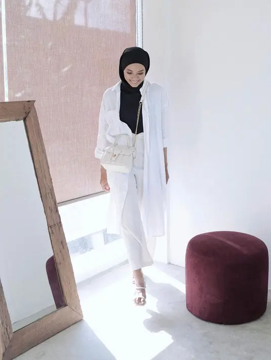 Tampil trendy ala monochrome saat di kantor dengan kemeja tunik berwarna putih yang dijadikan outer serta celana senada dan inner dan jilbab berwarna hitam. (instagram/ayudiac)