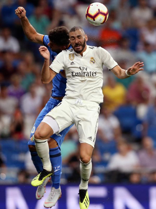 Penyerang Real Madrid, Karim Benzema berebut bola udara dengan pemain Getafe, Leandro Cabrera saat bertanding pada lanjutan La Liga Spanyol di stadion Santiago Bernabeu, Madrid, (19/8). Madrid menang 2-0 atas Getafe. (AP Photo/Andrea Comas)