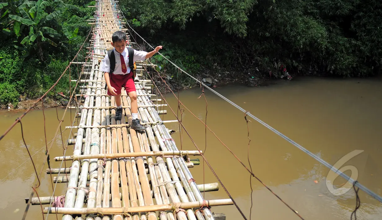 Seorang siswa SD melintas di atas jembatan gantung di atas kali Ciliwung untuk menuju ke sekolah, Jakarta, Selasa (17/3/2015). Jembatan tersebut menghubungkan Kelapa Dua Depok dengan Lenteng Agung (Liputan6.com/Yoppy Renato)