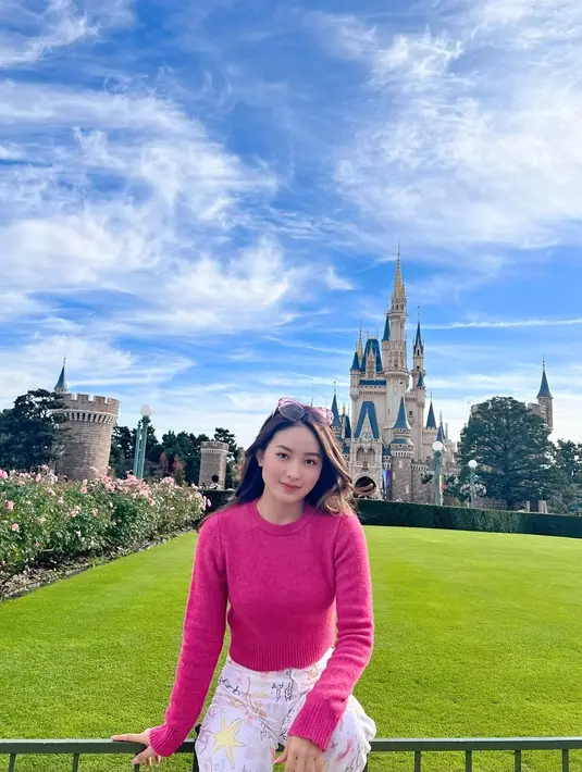 Main ke Tokyo Disneyland, Natasha Wilona tampil manis mengenakan sweatshirt pink fuschia dipadu high waisted pants bermotif.