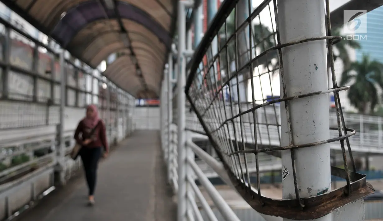Pejalan kaki saat melewati jembatan penyeberangan orang (JPO) yang berada di Jalan Sudirman, Jakarta, Rabu (17/4). JPO yang berada di tengah gedung-gedung perkantoran ini tidak terlihat terurus dan usang. (Merdeka.com/Iqbal Nugroho)