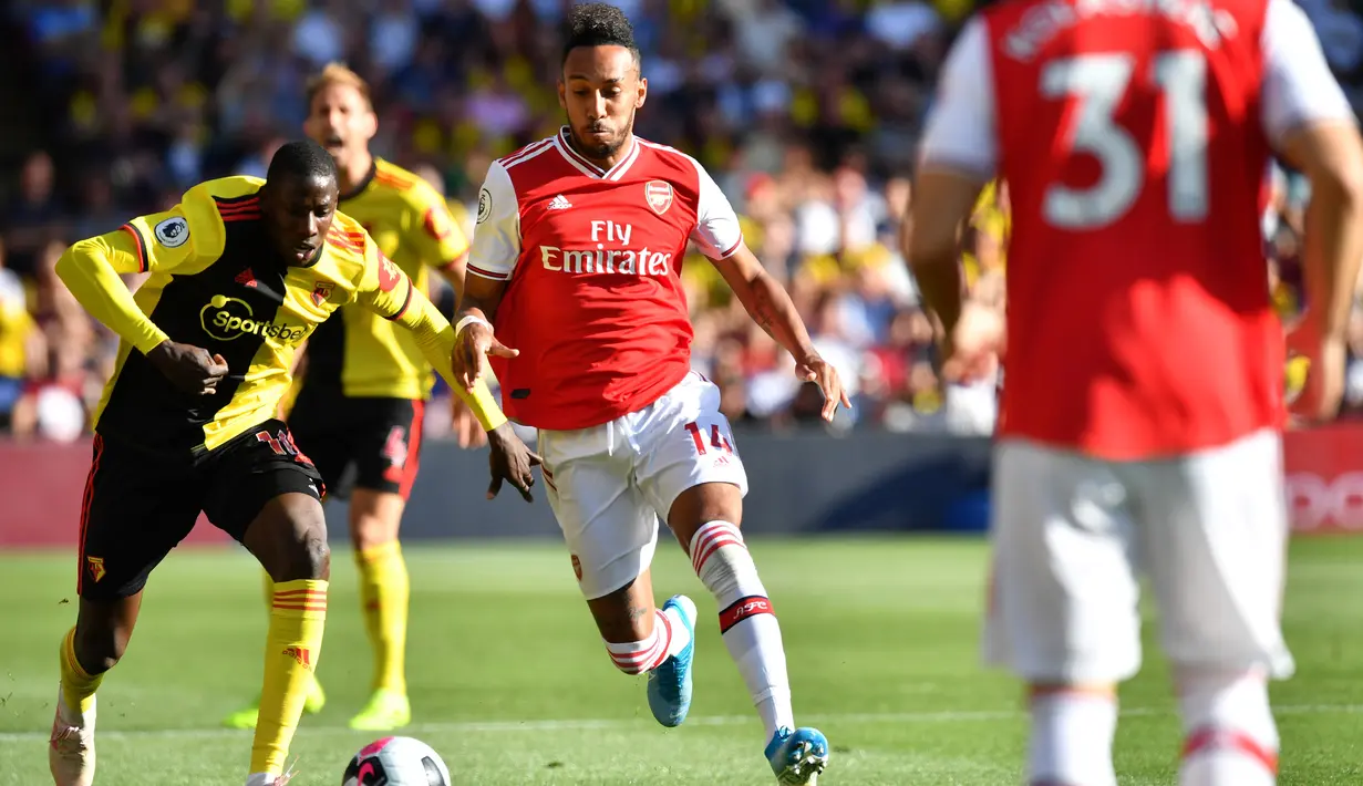 Gelandang Watford, Abdoulaye Doucoure, berebut bola dengan striker Arsenal, Pierre-Emerick Aubameyang, pada laga Premier League 2019/20 di Stadion Vicarage Road, Watford, Minggu (15/9). Kedua klub bermain imbang 2-2. (AFP/Ben Stansall)