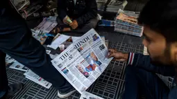 Penjual menata surat kabar yang sebagian besar menampilkan berita halaman depan tentang pemilihan presiden (Pilpres) AS, di jalan setapak di New Delhi, India pada Kamis (5/11/2020). (Photo by Jewel SAMAD / AFP)