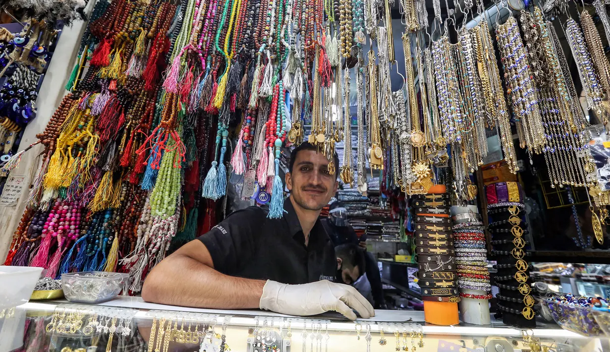 Pedagang mengenakan sarung tangan lateks menunggu pelanggan di tokonya selama bulan suci Ramadhan di Taheran, Iran (25/4/2020). Di pasar ini pedagang dan pembeli beraktivitas mengenakan alat pelindung seperti masker dan sarung tangan akibat pandemi coronavirus COVID-19. (AFP/Atta Kenare)