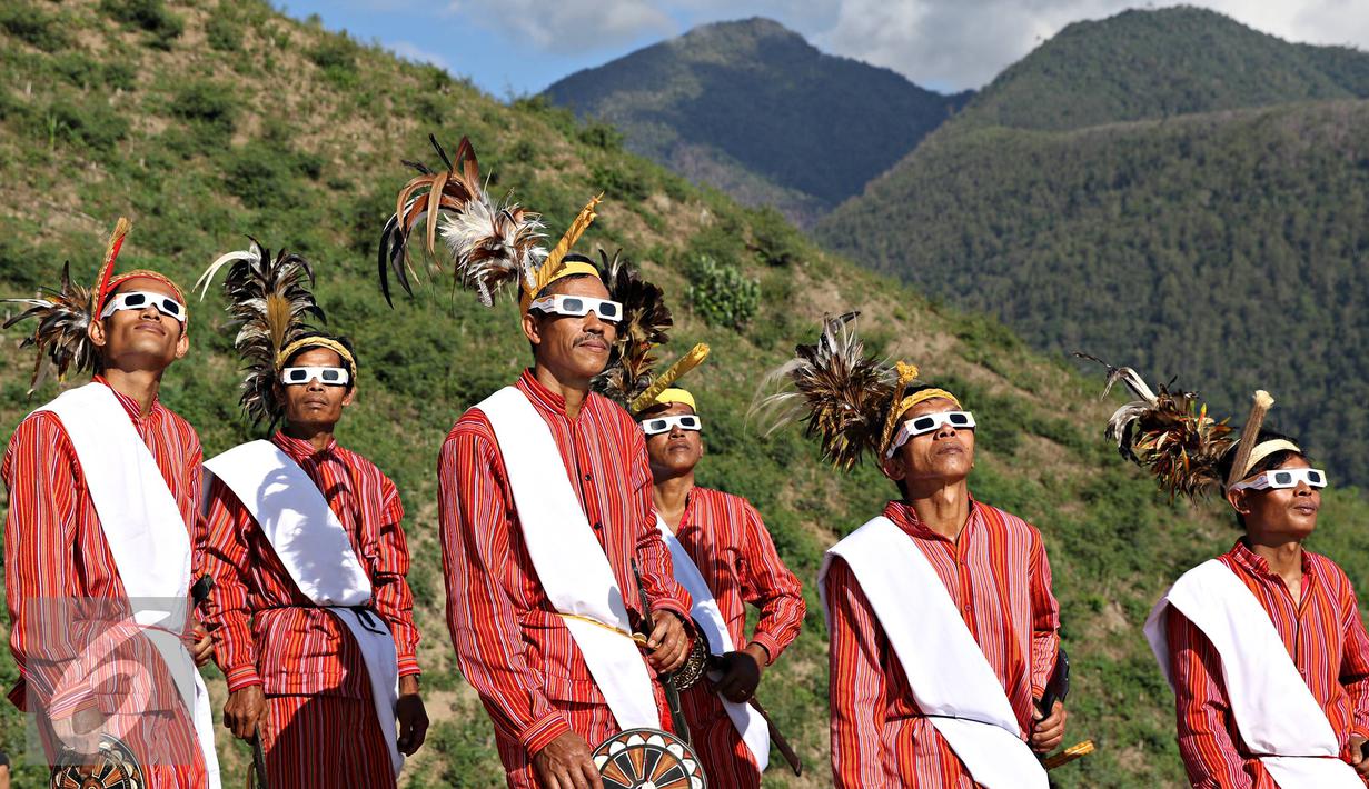 Seniman memakai kacamata melihat gerhana matahari di Bukit Matantimali, Sigi, Sulawesi Tengah, Rabu (9/3). Tarian tersebut dilakukan dalam rangka menyambut gerhana matahari total serta menolak bala. (Liputan6.com/Immanuel Antonius)