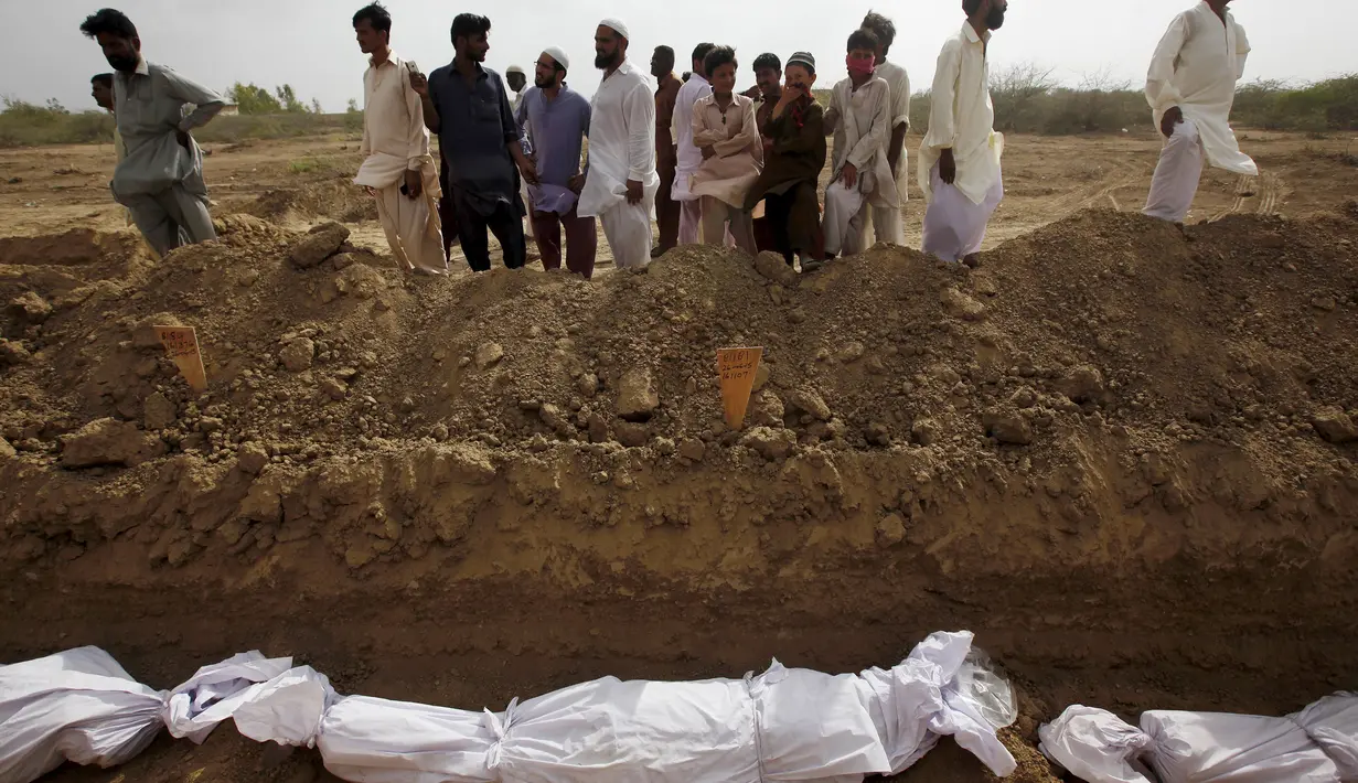 Sejumlah warga melihat proses pemakaman massal korban tewas akibat gelombang panas di Karachi, Pakistan, Jumat (26/6/2015). Lebih dari 1.150 orang tewas akibat gelombang panas. (REUTERS/Akhtar Soomro)
