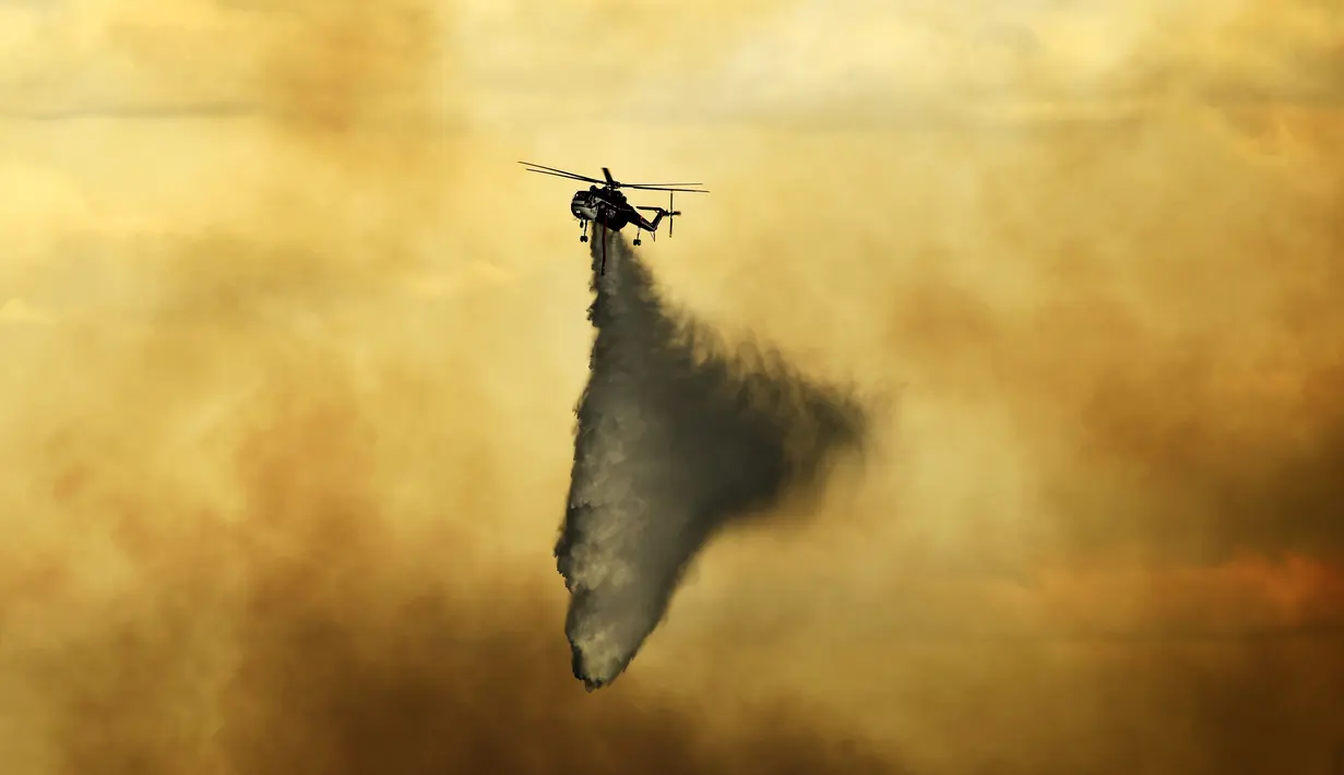 Helikopter menjatuhkan tembakan pada api yang terbakar di dekat Evergreen, Colo (13/7/2020). Cuaca dingin dan hujan yang turun memberikan harapan kepada petugas pemadam kebakaran untuk dapat mengendalikan api yang menyebabkan kebakaran di wilayah tersebut. (RJ Sangosti/The Denver Post via AP)