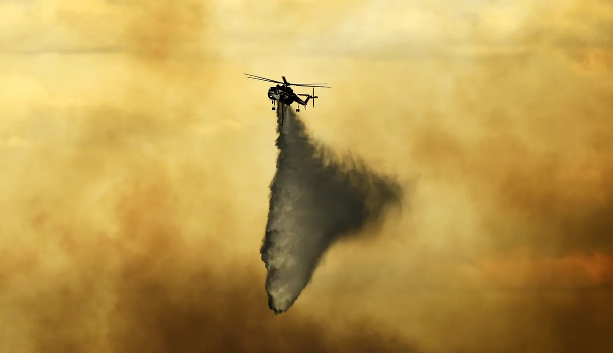 Helikopter menjatuhkan tembakan pada api yang terbakar di dekat Evergreen, Colo (13/7/2020). Cuaca dingin dan hujan yang turun memberikan harapan kepada petugas pemadam kebakaran untuk dapat mengendalikan api yang menyebabkan kebakaran di wilayah tersebut. (RJ Sangosti/The Denver Post via AP)
