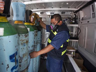 Petugas kesehatan Jose Antonio Pena mengisi ulang tangki oksigen untuk pasien COVID-19 di Distrik Iztapalapa, Mexico City, Meksiko, Selasa (26/1/2021). Mexico City menawarkan isi ulang oksigen gratis untuk pasien COVID-19. (AP Photo/Marco Ugarte)