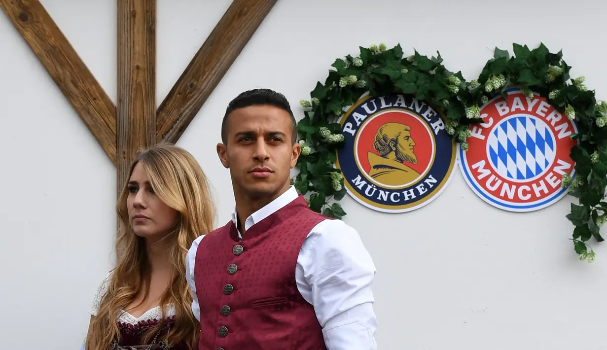 Gelandang Bayern Munchen, Thiago Alcantara bersama sang istri, Julia Vigas, mengenakan gaun tradisional Bavaria saat menikmati akhir dengan mengunjungi festival bir tahunan Oktoberfest di Munich, Jerman, Minggu (7/10). (Christof STACHE / AFP)