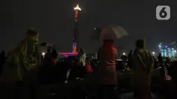 Pengunjung menyaksikan penampilan video mapping saat malam pergantian tahun di kawasan Monumen Nasional, Jakarta, Selasa (31/12/2019). Penampilan video mapping mewarnai kemeriahan malam pergantian tahun baru di kawasan Monumen Nasional, Jakarta. (Liputan6.com/Helmi Fithriansyah)