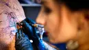 Seniman wanita mentato badan pengunjung dalam acara edisi keempat Montreux Tattoo Convention di Montreux, Swiss  (22/9). Lebih 150 seniman tato dari 22 negara berkumpul dalam acara tersebut. (Valentin Flauraud/Keystone via AP)