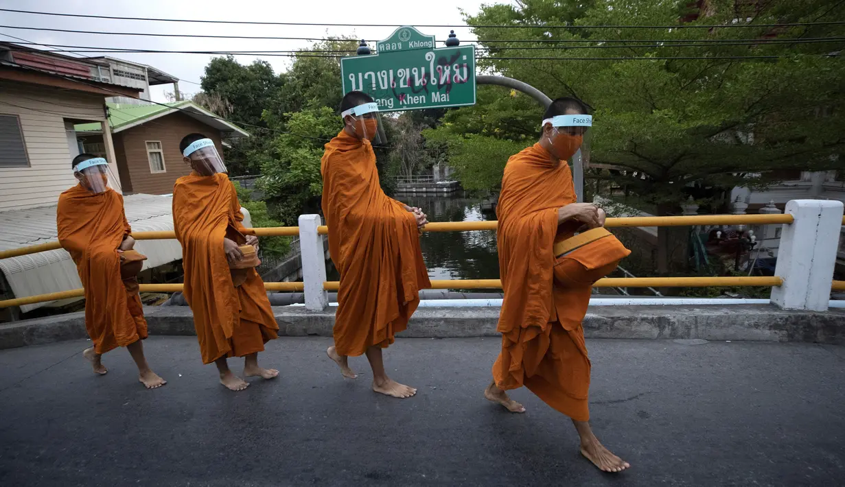 Para biksu Buddha memakai pelindung wajah untuk melindungi diri dari virus corona COVID-19 saat mengumpulkan sedekah di Bangkok, Thailand, Selasa (31/3/2020). Hingga 30 Maret 2020 sore, jumlah kasus COVID-19 di Thailand sebanyak 1.524 positif, 229 sembuh, dan 9 meninggal. (AP Photo/Sakchai Lalit)