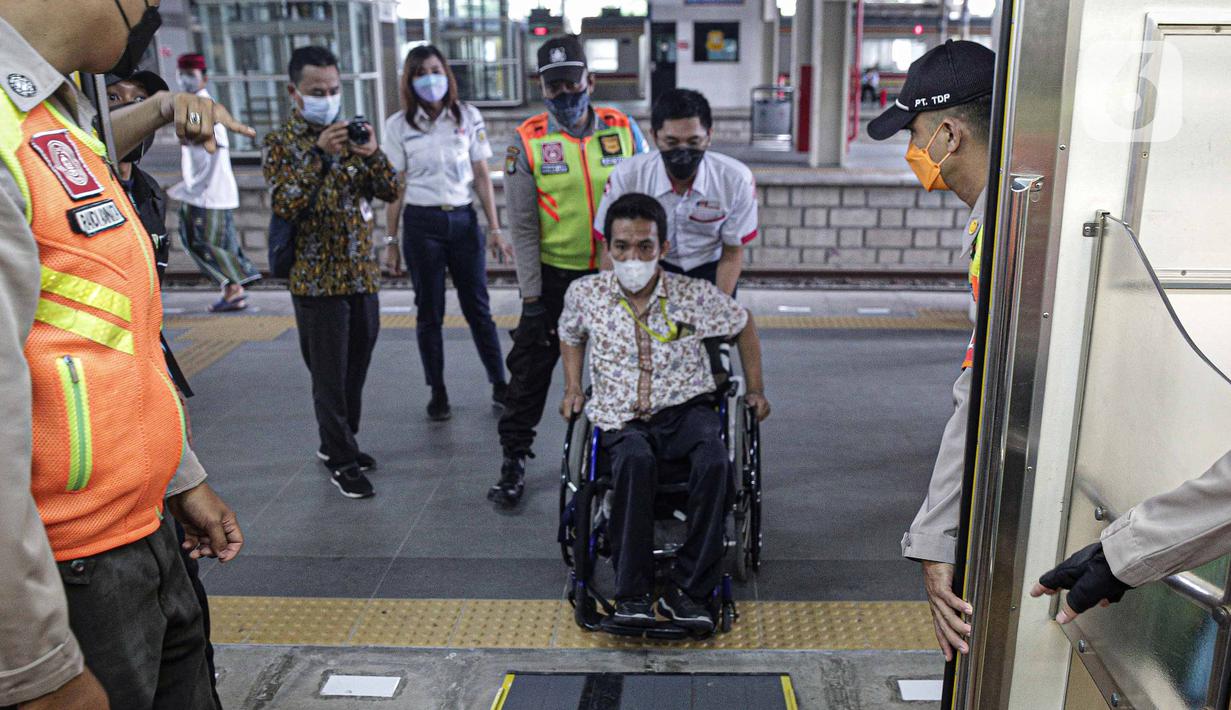 Petugas membantu penyandang disabilitas naik ke kereta saat menjajal fasilitas di Stasiun Jatinegara, Jakarta, Jumat (3/12/2021). KAI Commuter mengajak pengguna transportasi dengan disabilitas untuk merasakan sarana dan prasarana perkeretaapian yang lebih aksesibel. (Liputan6.com/Faizal Fanani)