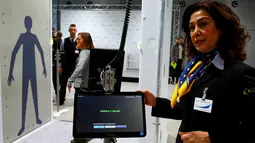 Petugas mengawasi calon penumpang yang hendak melewati Mesin deteksi full body terbaru Bandara Cologne-Bonn Konrad Adenaue, Jerman (15/11). Mesin ini akan secara otomatis mendeteksi benda-benda yang berpotensi bahaya. (REUTERS/Wolfgang Rattay)