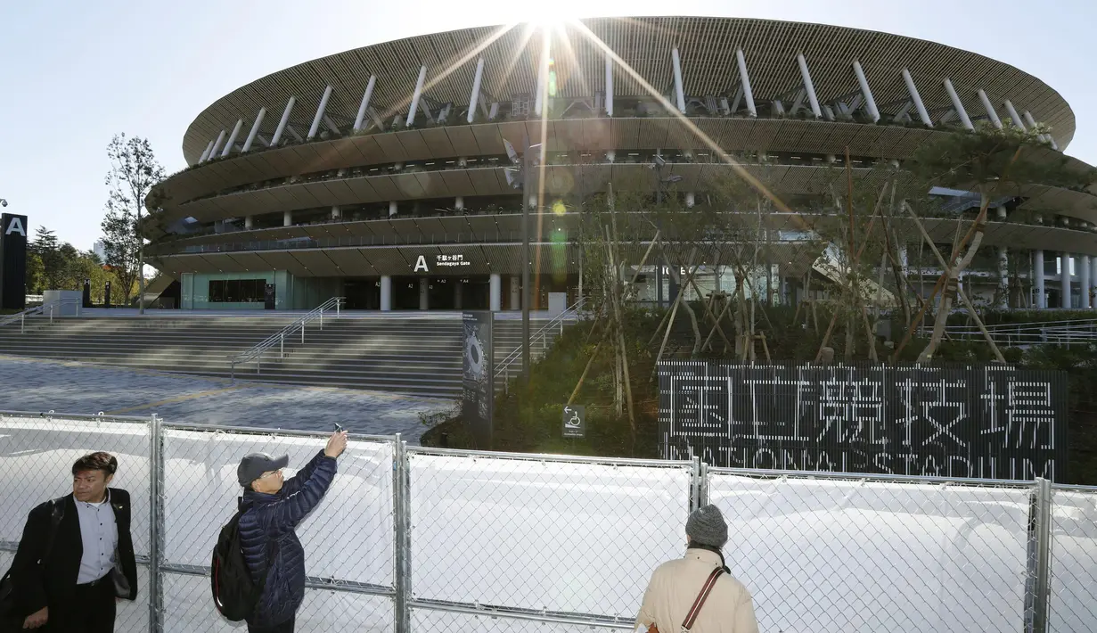 Orang-orang melihat Stadion Nasional Tokyo untuk Olimpiade dan Paralimpiade Tokyo 2020 setelah selesai direnovasi di Tokyo (30/11/2019). tadion berkapasitas 60 ribu itu akan menjadi venue upacara pembukaan serta berbagai nomor atletik dan cabang sepak bola. (Masanori Takei/Kyodo News via AP)