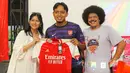 Salah seorang peserta Roaring Night pertandingan Liga Inggris 2023/2024 antara Arsenal kontra Crystal Palace yang beruntung mendapatkan merchandise berupa jersey original Arsenal berfoto bersama MC Eddi Brokoli dan pengurus Arsenal Indonesia Supporters (AIS) di Bucketlist Indonesia, Bogor, Sabtu (20/1/2024). (Bola.com/Bagaskara Lazuardi)