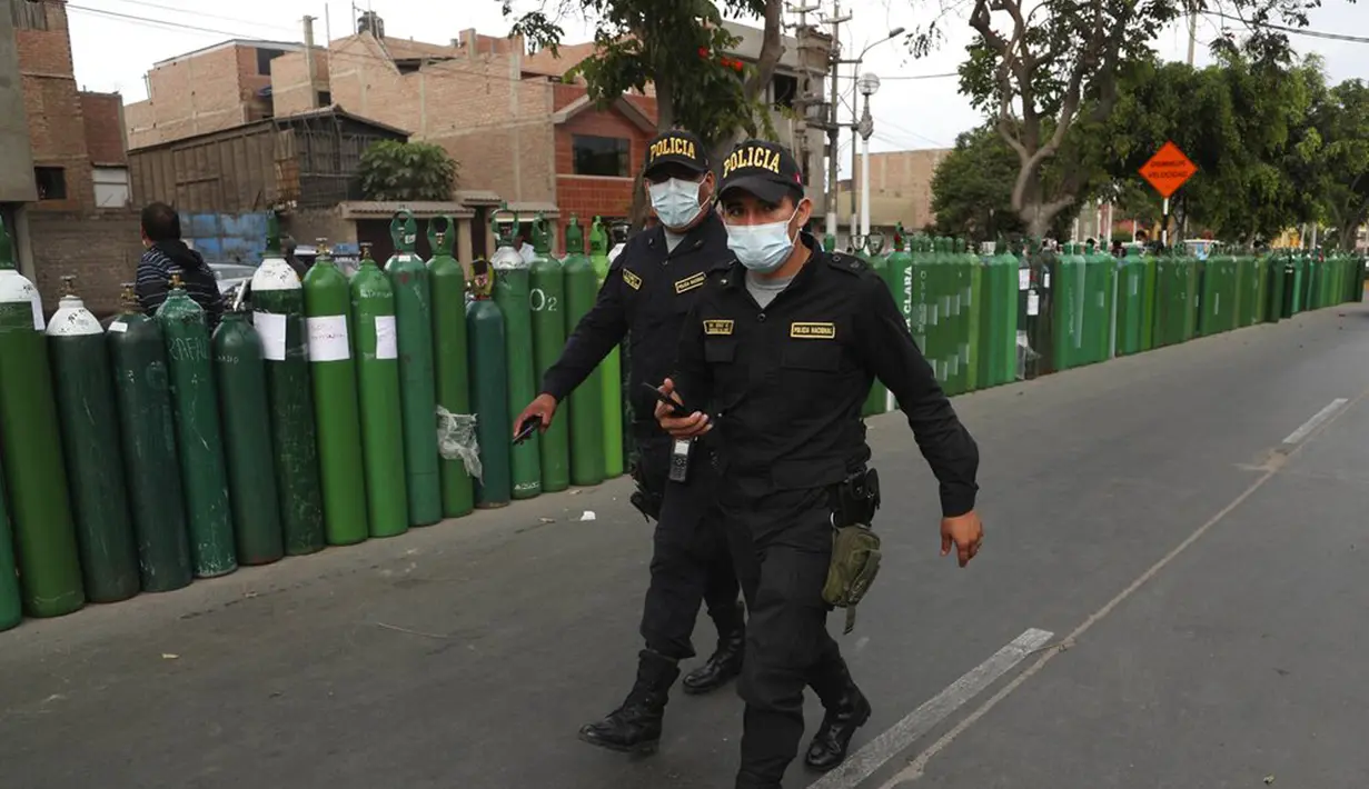 Polisi membantu menjaga ketertiban di luar toko isi ulang tangki oksigen di Callao, Peru, Senin (25/1/2021). Di tengah pandemi COVID-19, beberapa orang mengatakan mereka telah antre sehari sebelumnya untuk menjadi yang pertama saat toko buka. (AP Photo/Martin Mejia)