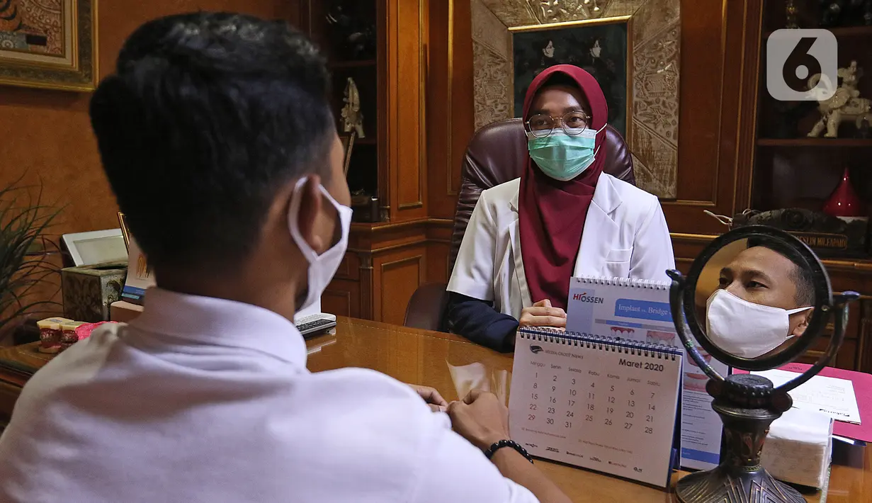 drg. Ayusha berbincang dengan pasien di salah satu klinik di kawasan Pulo Gadung, Jakarta, Rabu (22/4/2020). Di tengah pandemi COVID-19 seperti sekarang ini, drg. Ayusha akan mengenakan alat perlindungan diri (APD) saat memeriksa pasien. (Liputan6.com/Herman Zakharia)