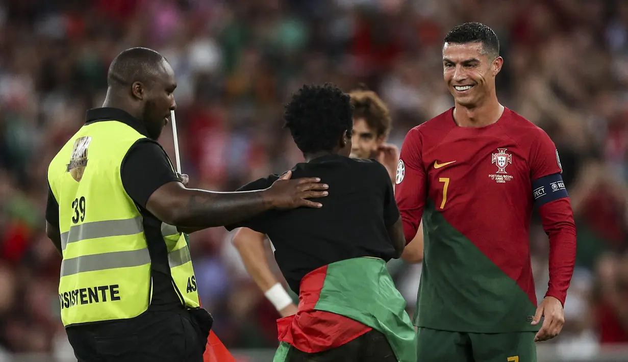 Setelah bersimpuh, sang suporter mengangkat tubuh Ronaldo dengan kedua tangannya. (Photo by CARLOS COSTA / AFP)
