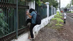 Warga menerobos pagar usai menyeberangi rel kereta api di kawasan Lenteng Agung, Jakarta, Selasa (19/3). Tidak adanya JPO menyebabkan warga harus menerobos pagar besi, meskipun perilaku tersebut berbahaya bagi keselamatan. (Liputan6.com/Immanuel Antonius)