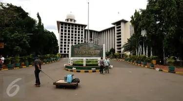 Pedagang melintas di depan pintu masuk utama Masjid Istiqlal Jakarta, Kamis (3/11). Jelang demo besar besaran Jumat (4/11), aktivitas warga di Masjid Istiqlal terlihat normal dan kondusif. (Liputan6.com/Helmi Fithriansyah)