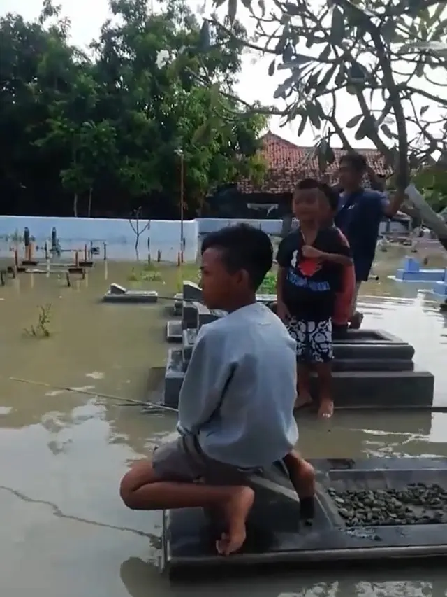 Sekumpulan pemuda dan bapak-bapak pancing ikan di kuburan.