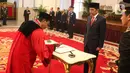 Presiden Joko Widodo (Jokowi) menyaksikan Daniel Yusmic Pancastaki menandatangi dokumen pelantikan Hakim Mahkamah Konstitusi di Istana Negara, Selasa (7/1/2020). Jokowi melantik Suhartoyo dan Daniel Yusmic Pancastaki Foekh sebagai Hakim Konstitusi periode 2020-2025. (Liputan6.com/Angga Yuniar)