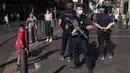 Polisi anti huru-hara Prancis mengamati warga yang mengenakan masker di Marseille, Selasa (18/8/2020). Pemerintah Prancis mengirim polisi anti huru hara ke wilayah Marseille untuk membantu menegakkan peraturan penggunaan masker saat negara itu mencatat lonjakan kasus COVID-19. (AP Photo/Daniel Cole)