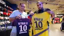 Dua orang fans menunjukan jersey pemain Paris Saint Germain, Neymar Jr, di toko merchandise di Paris, Jumat (4/8/2017). Setelah resmi bergabung dengan Paris Saint Germain, jersey Neymar Jr langsung diburu suporter klub Ibu kota. (AP/Michel Euler)