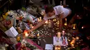 Seorang pria menyalakan lilin sehari setelah serangan bunuh diri di sebuah konser Ariana Grande di Albert Square, Manchester, Inggris, (23/5). Kejadian ini menyebabkan 22 orang tewas  dan melukai 119 lainnya. (AP Photo/Emilio Morenatti)