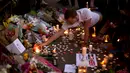 Seorang pria menyalakan lilin sehari setelah serangan bunuh diri di sebuah konser Ariana Grande di Albert Square, Manchester, Inggris, (23/5). Kejadian ini menyebabkan 22 orang tewas  dan melukai 119 lainnya. (AP Photo/Emilio Morenatti)
