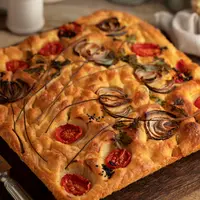 Focaccia bisa dihidangkan dengan berbagai jenis topping, seperti tomat dan keju yang meleleh. (Foto/dok: Freepik)