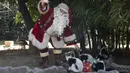 Seorang pria berpakaian Sinterklas memberikan hadiah berupa makanan kepada para hewan sebagai bagian dari tradisi Natal di Kebun Binatang La Aurora, Kota Guetemala, Selasa (20/12/2022). Pengunjung dapat melihat kandang-kandang hewan yang terdapat kotak kado tertata rapih. (Orlando ESTRADA / AFP)