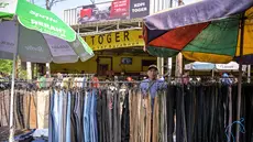 Seorang pedagang menata celana panjang sambil menunggu pelanggan pakaiannya di salah satu ruas jalan, Surabaya, Jawa Timur, pada Minggu 19 April 2026. Badan Pusat Statistik (BPS) Republik Indonesia akan melaksanakan Sensus Ekonomi 2026 (SE2026). (JUNI KRISWANTO/AFP)