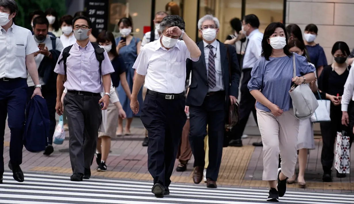 Orang-orang mengenakan masker mencegah penyebaran coronavirus baru berjalan di atas penyeberangan pejalan kaki di Tokyo, Senin, (20/7/2020). Ibukota Jepang hari Senin mengkonfirmasi lebih dari 160 kasus virus corona baru. (AP Photo/Eugene Hoshiko)