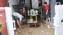 Warga membersihkan lumpur sisa banjir di halaman rumahnya di perumahan Ciledug Indah, Tangerang, Senin (21/2/2021). Banjir yang menggenangi perumahan tersebut membuat warga mengalami kerugian cukup besar karena barang-barang berharga mereka rusak parah. (Liputan6.com/Angga Yuniar)