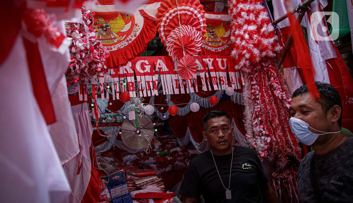 Pedagang melayani pembeli pernak pernik HUT Republik Indonesia di Pasar Jatinegara, Jakarta, Selasa (10/8/2021). Dua tahun pandemi Covid-19 berjalan, penjual pernak pernik hingga bendera merah putih  turun rata-rata 50-70 persen. (Liputan6.com/Faizal Fanani)