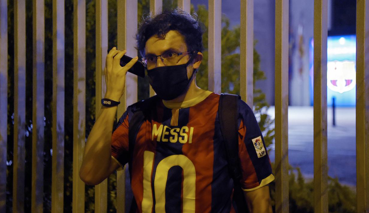 Suporter memakai jersey Lionel Messi mengikuti protes di depan kantor Barcelona, Selasa (25/8/2020). Aksi tersebut merupakan respon fans atas kabar Lionel Messi yang akan meninggalkan Camp Nou pada musim panas ini. (AFP/Pau Barrena)