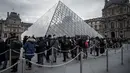 Pengunjung mengantre di luar Pyramid, pintu masuk utama menuju museum Louvre, di Paris, Rabu (4/3/2020). Louvre di Paris, museum yang paling banyak dikunjungi di dunia, kembali dibuka setelah pegawai yang khawatir dengan penularan virus corona setuju kembali masuk kerja. (Philippe LOPEZ/AFP)