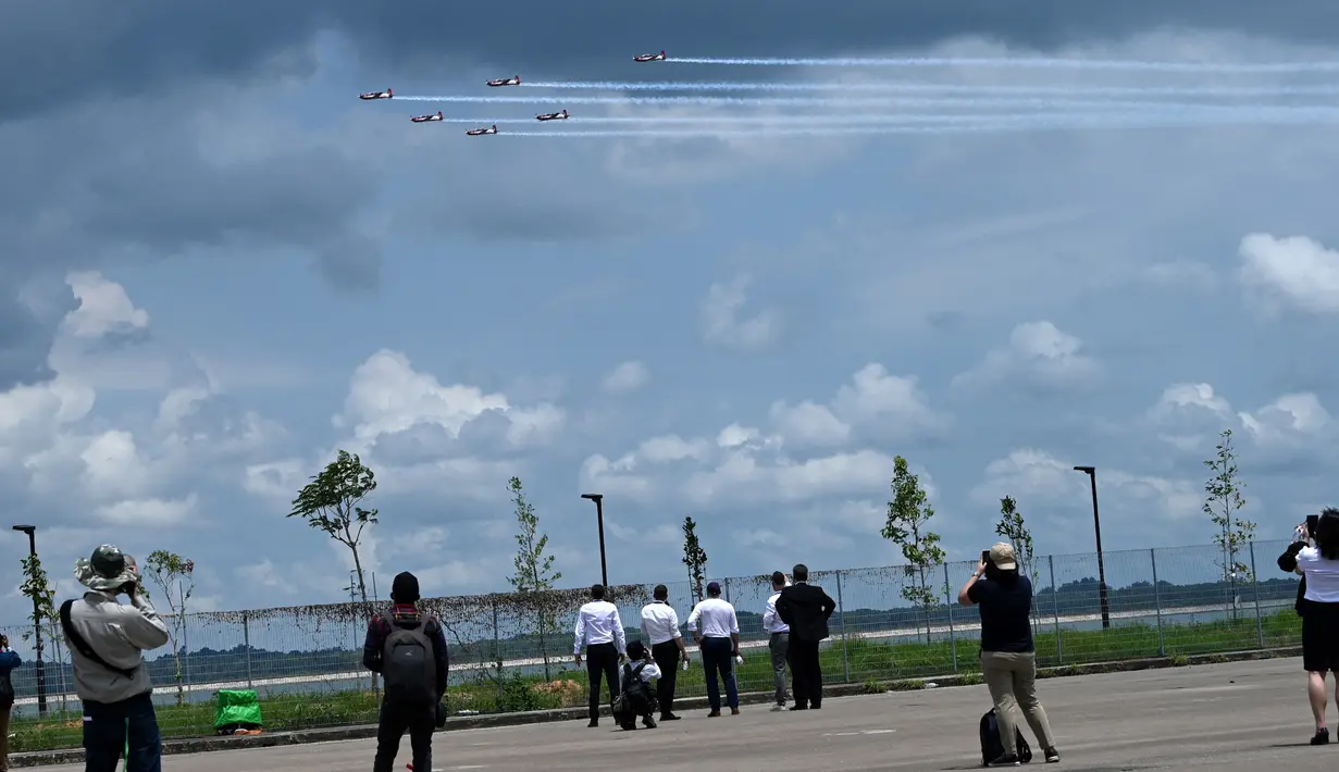 Orang-orang menyaksikan penampilan Jupiter Aerobatic Team TNI AU yang menerbangkan pesawat KT-1 pada pertunjukan udara Singapore Airshow 2022 di Changi Exhibition Centre, Singapura, 15 Februari 2022. Singapore Airshow 2022 berlangsung pada 15 hingga 18 Februari. (ROSLAN RAHMAN/AFP)