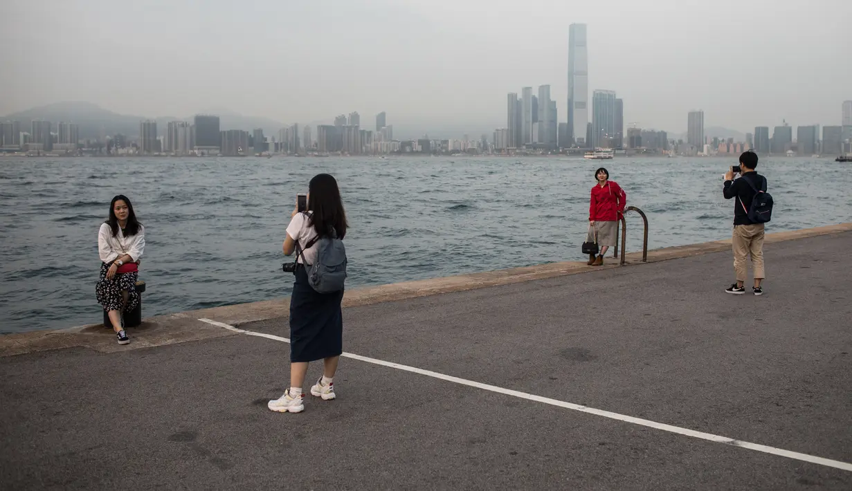 Orang-orang mengambil foto di dermaga umum di sebelah Pelabuhan Victoria di Hong Kong (3/3). Pelabuhan Victoria adalah sebuah pelabuhan bentang alam alami yang terletak antara Pulau Hong Kong dan Kowloon di Hong Kong. (AFP Photo/Dale De La Rey)