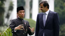 Presiden Joko Widodo (kiri) berbincang dengan Emir Qatar Syekh Tamim bin Hamad Al Thani sebelum menanam pohon eboni di Istana Bogor, Jawa Barat, Rabu (18/10). Usai penanaman pohon, keduanya melakukan pertemuan bilateral. (Beawiharta/Pool photo via AP)
