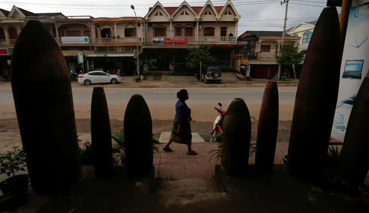 Seorang wanita berjalan melewati sebuah restoran dihiasi dengan bom dan belum meledak yang dijatuhkan oleh pesawat-pesawat Angkatan Udara AS selama Perang Vietnam, di Desa Ban Napia, Provinsi Xieng Khouang, Laos (03/9). (REUTERS/Jorge Silva)