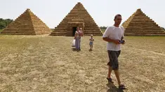 Wisatawan berjalan di sekitar replika Piramida Giza yang terbuat dari jerami di permukiman Krasnoye, Rusia, Rabu (19/7). Piramida unik itu salah satu bangunan yang menghiasi taman jerami di wilayah pertanian Ponomaryovo. (REUTERS/Eduard Korniyenkov)