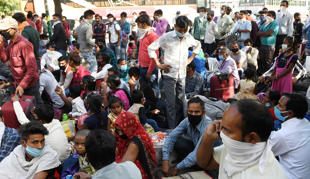 Pekerja migran yang terdampar dan keluarga mereka berkumpul menunggu pemeriksaan medis sebelum pergi dengan kereta api untuk kembali ke kota asal mereka ke Jaunpur, negara bagian Uttar Pradesh, setelah pemerintah melonggarkan lockdown di Amritsar, India, Selasa (19/5/2020). (NARINDER NANU/AFP)