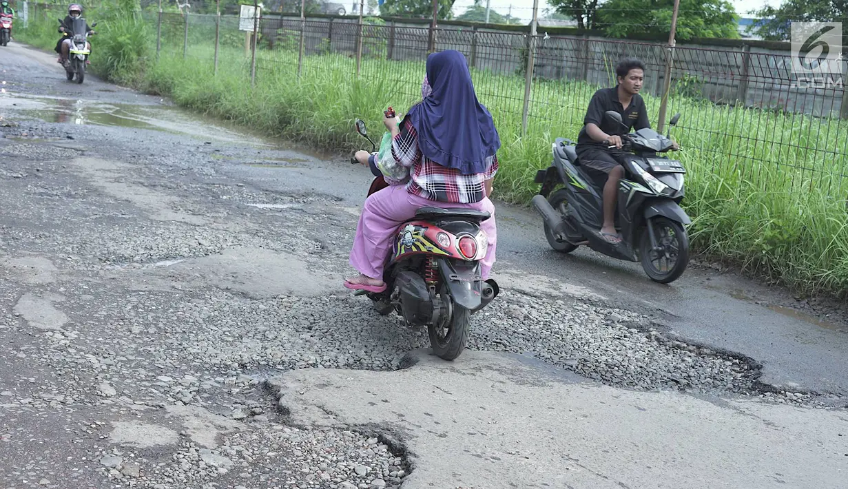 Pengendara sepeda motor melintasi jalan yang rusak di Jalan Raya Gas Alam, Depok, Jawa Barat, Selasa (7/5). Kondisi jalan yang tidak kunjung diperbaiki tersebut menjadi kubangan air setiap hujan serta berbahaya bagi keselamatan pengguna jalan. (Liputan6.com/Immanuel Antonius)