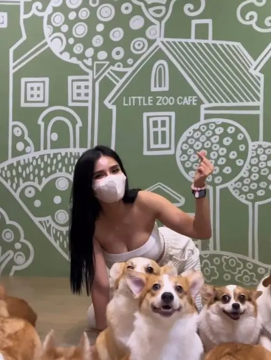 Maria Vania saat berpose dikelilingi anjing-anjing saat mengunjungi Little Zoo Cafe. Ia juga Berpose dengan gesture i love u ala Korea. (Instagram/maria_vaniaa)