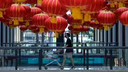 Seorang pembeli berjalan di lorong mal dengan dekorasi lentera untuk perayaan Tahun Baru Imlek di Kuala Lumpur, Malaysia, Rabu (3/2/2021). Imlek tahun ini jatuh pada tanggal 12 Februari 2021. (Mohd RASFAN/AFP)